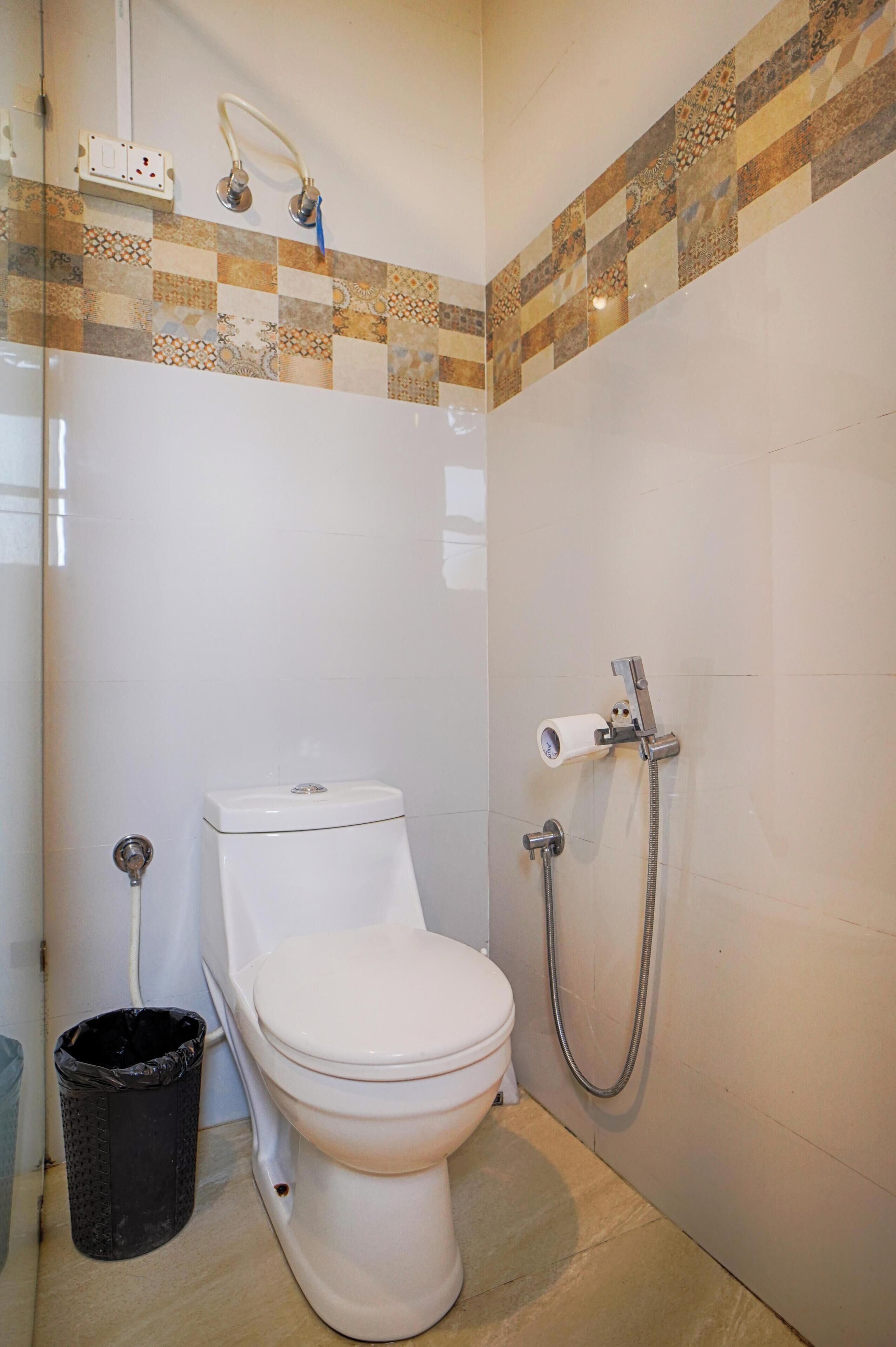 A bathroom with a toilet, a shower, and a trash bin.