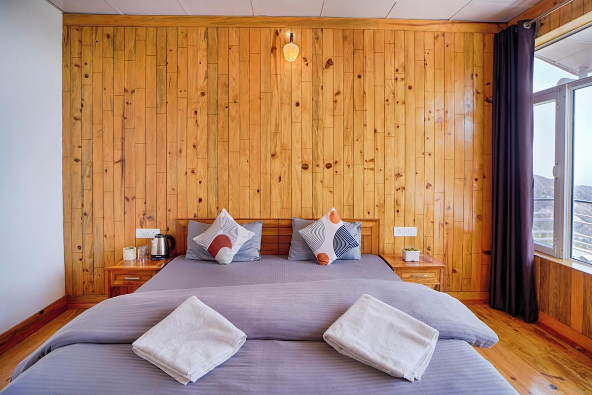 A wooden-paneled bedroom with a large bed, two bedside tables, and a window with curtains.
