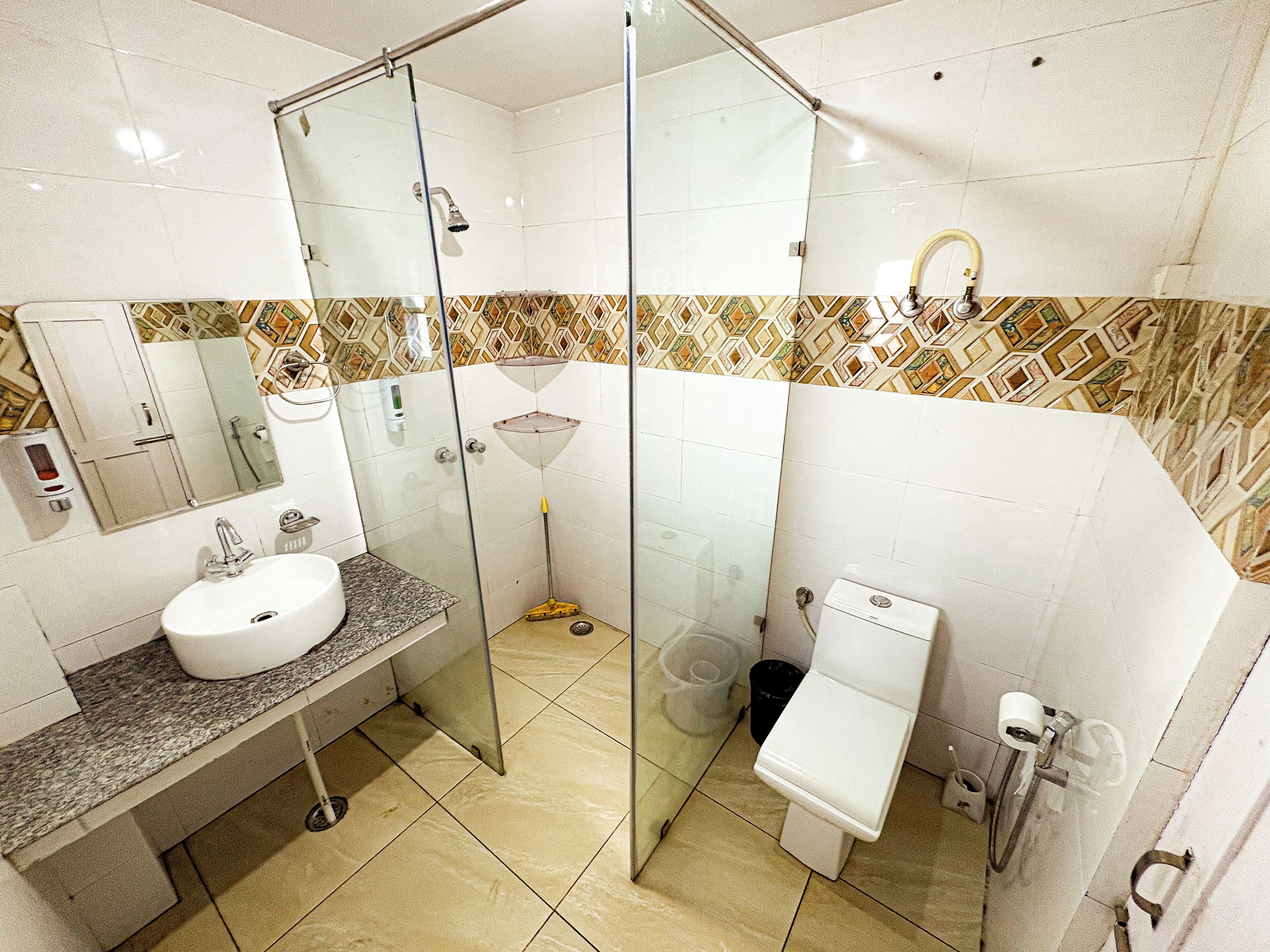 A bathroom with a glass-enclosed shower, a sink, a toilet, and a mirror.