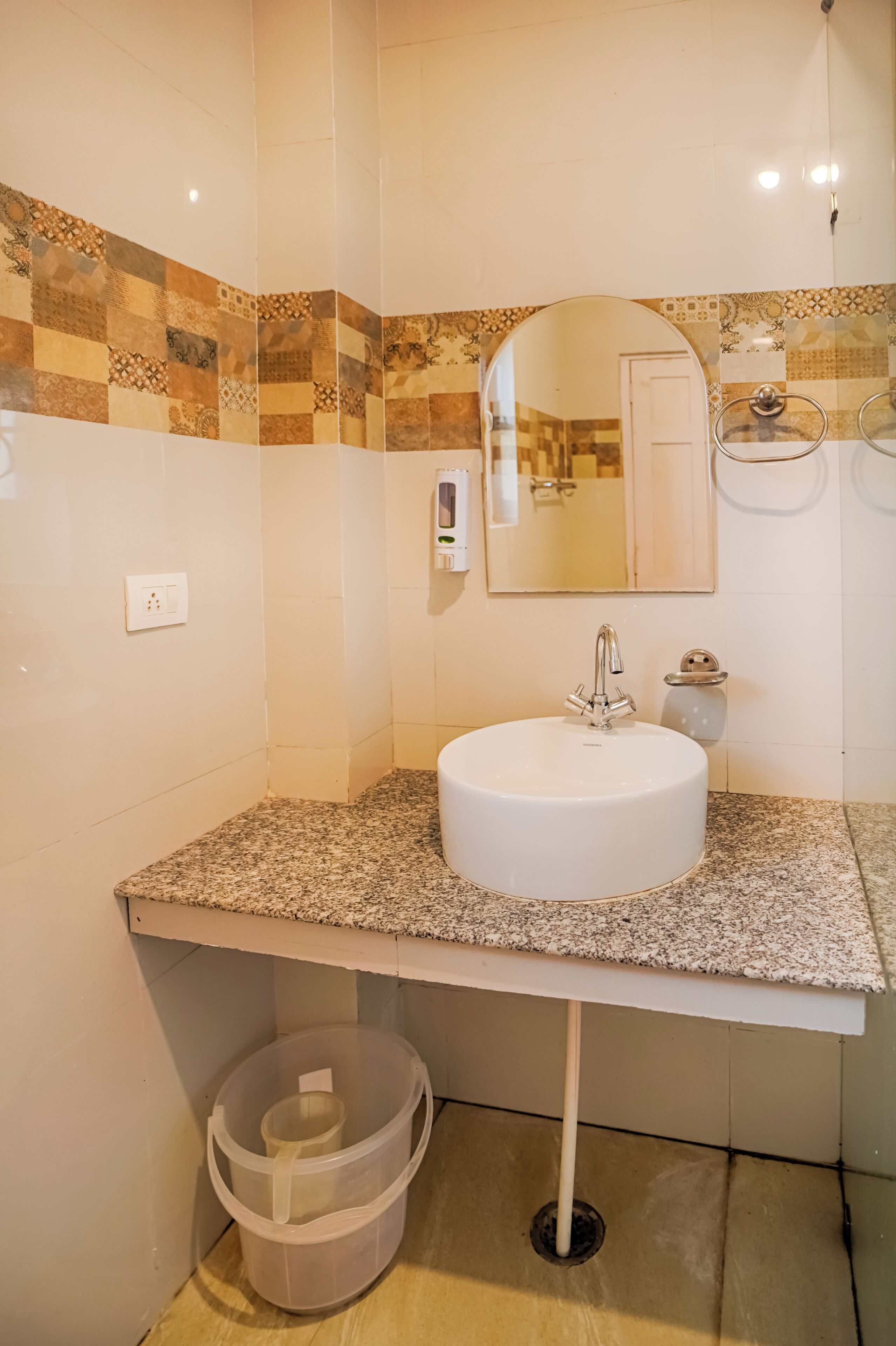 A bathroom with a white sink, a mirror, and a patterned tile backsplash.