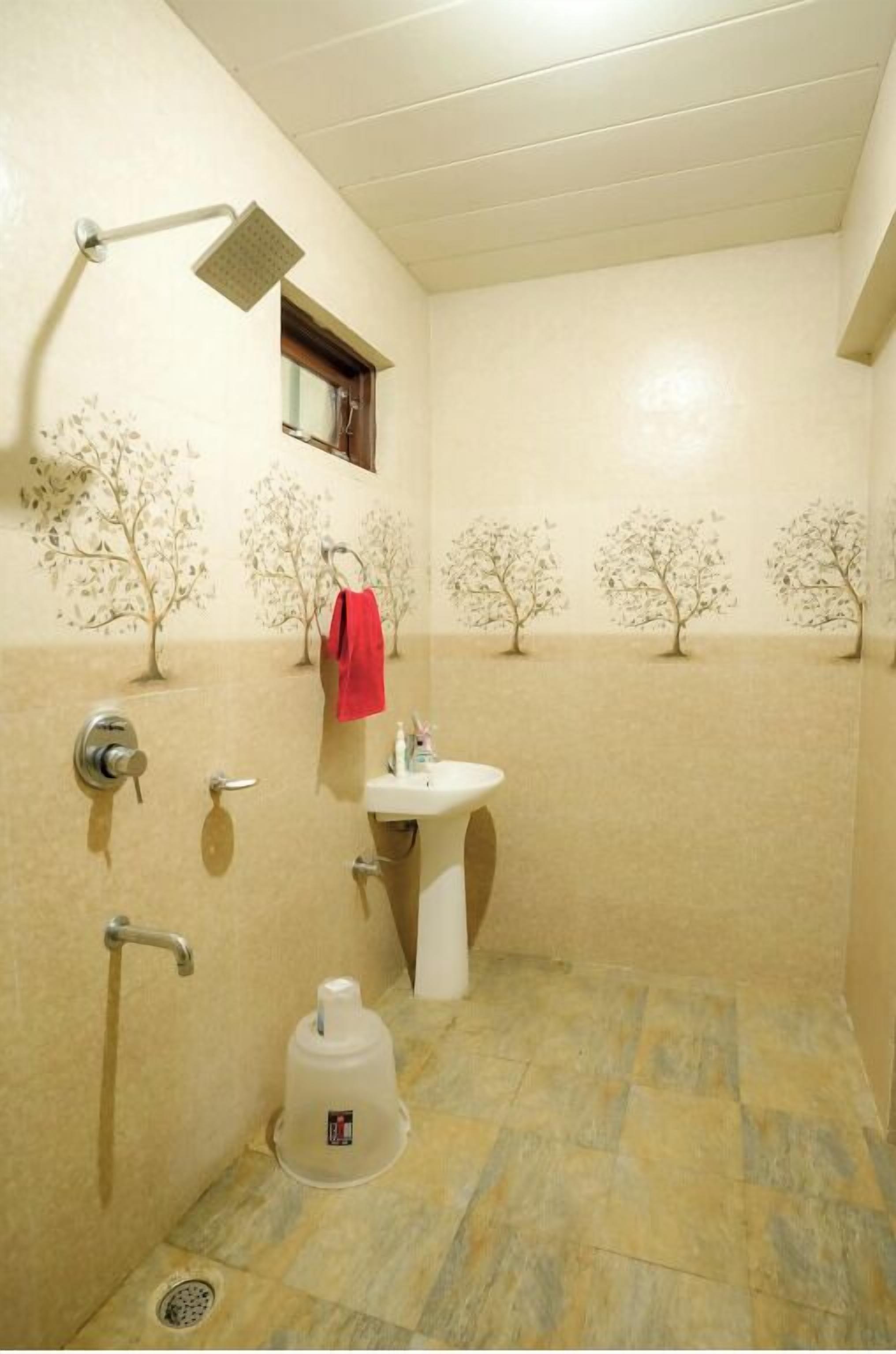 A bathroom with a shower, sink, and a red towel hanging on the wall.