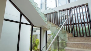 Un escalier moderne avec des rampes en verre et une vue sur la verdure environnante.