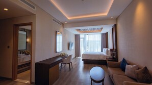 Une chambre d’hôtel avec un lit, un bureau, un canapé et une petite table.