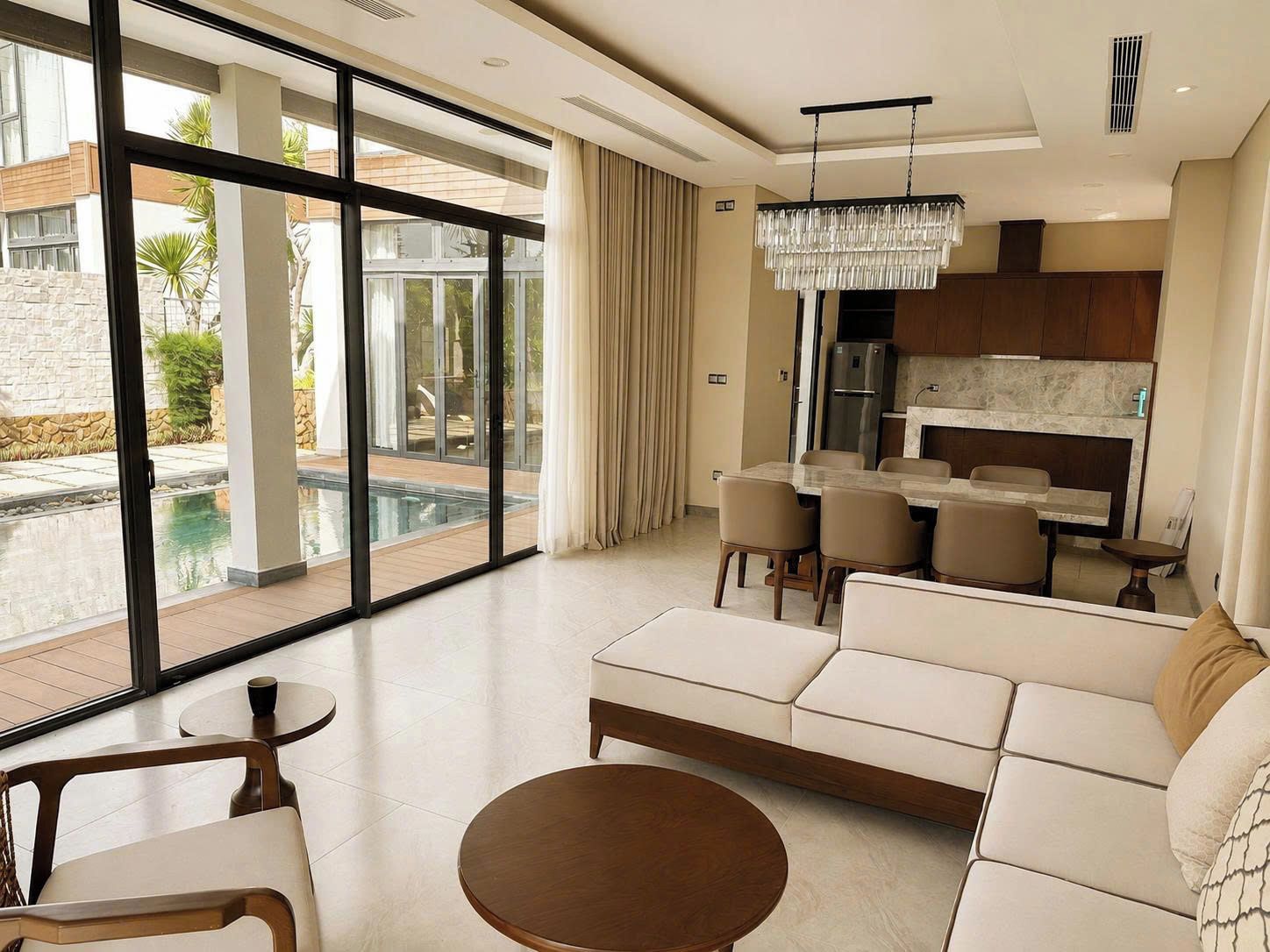 A modern living room with a large window, a dining area, and a kitchen.