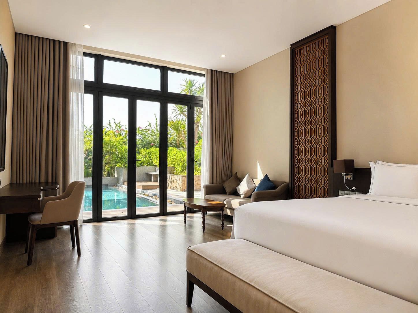A hotel room with a large bed, a desk, and a view of a swimming pool.