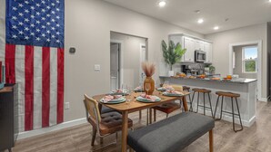 Una cocina moderna con armarios blancos, una isla grande y una zona de comedor con mesa para cuatro.
