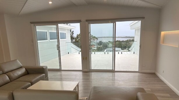 Uma sala de estar ampla com uma grande porta de vidro deslizante que dá para uma varanda.