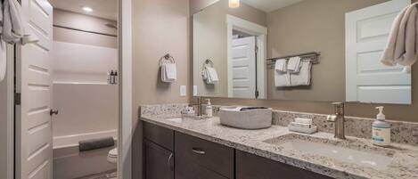 Un baño moderno con tocador, lavamanos y espejo.
