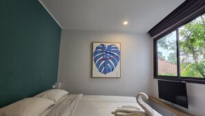 Een hotelkamer met een bed, een groot raam, een flatscreen televisie en een kunstwerk aan de muur.