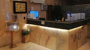 A reception area with a marble counter, a clock, an air conditioning unit, and a chandelier. - fakhamat almasif (Taif)