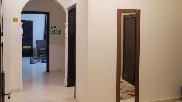 A hallway with a tiled floor, an arched doorway, and a door frame. - fakhamat almasif (Taif)