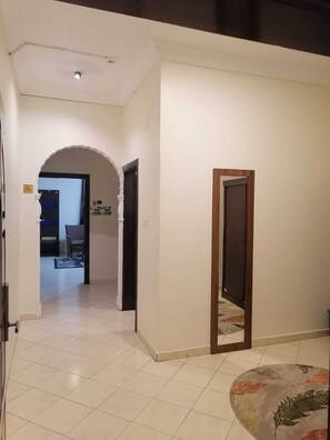 A hallway with a tiled floor, an arched doorway, and a door frame. - fakhamat almasif (Taif)