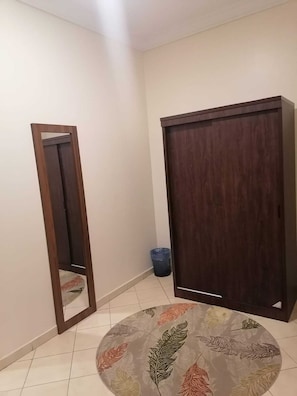 Una habitación con un armario de madera, un espejo y un tapete redondo con motivos de hojas.