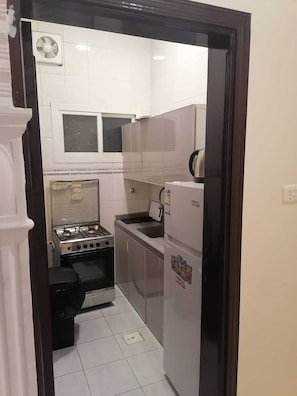 A compact kitchen with a gas stove, a sink, and a refrigerator. - fakhamat almasif (Taif)
