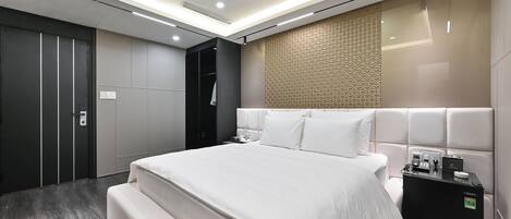 Una habitación de hotel moderna con una cama grande, armario empotrado, minibar y un diseño de pared con textura.