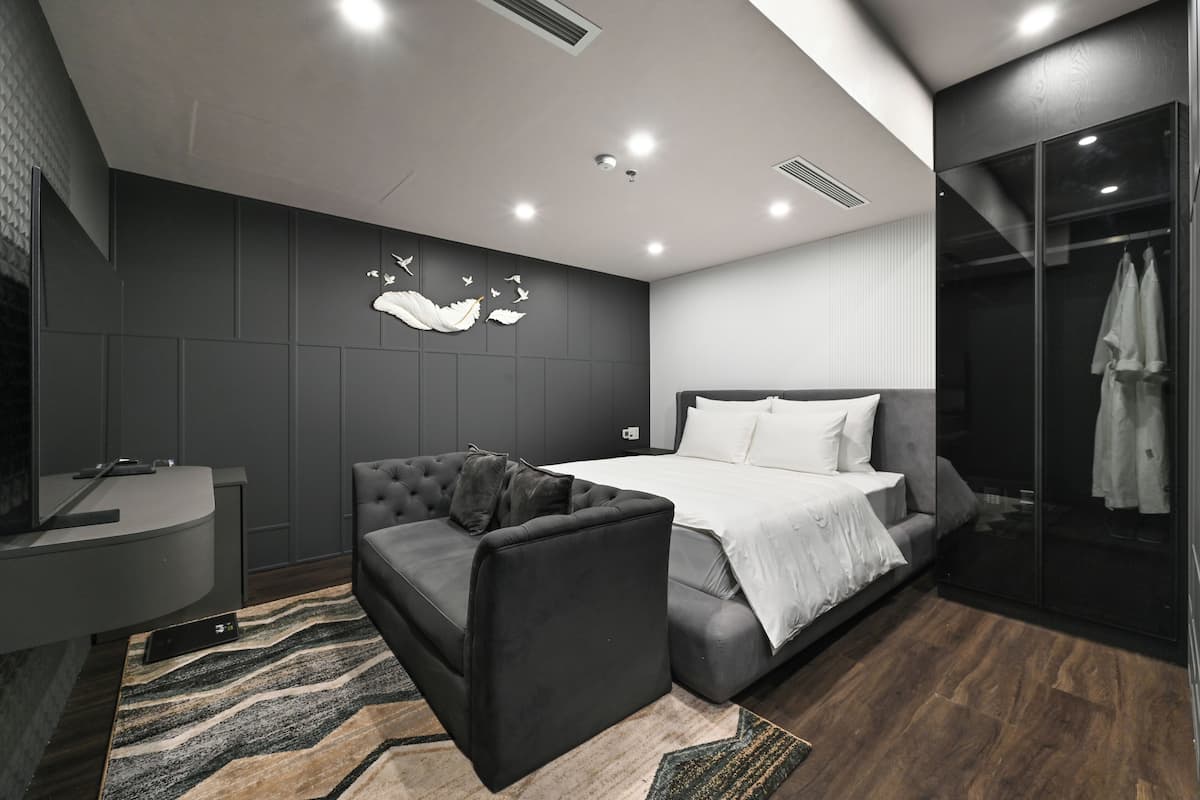Une chambre moderne comprenant un lit, un canapé, une coiffeuse et un espace douche.