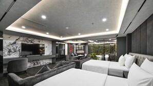 A modern hotel room with a large bed, a sofa, a TV, and a glass shower area. - Accord Hotel Binh Tan (Ho Chi Minh City)