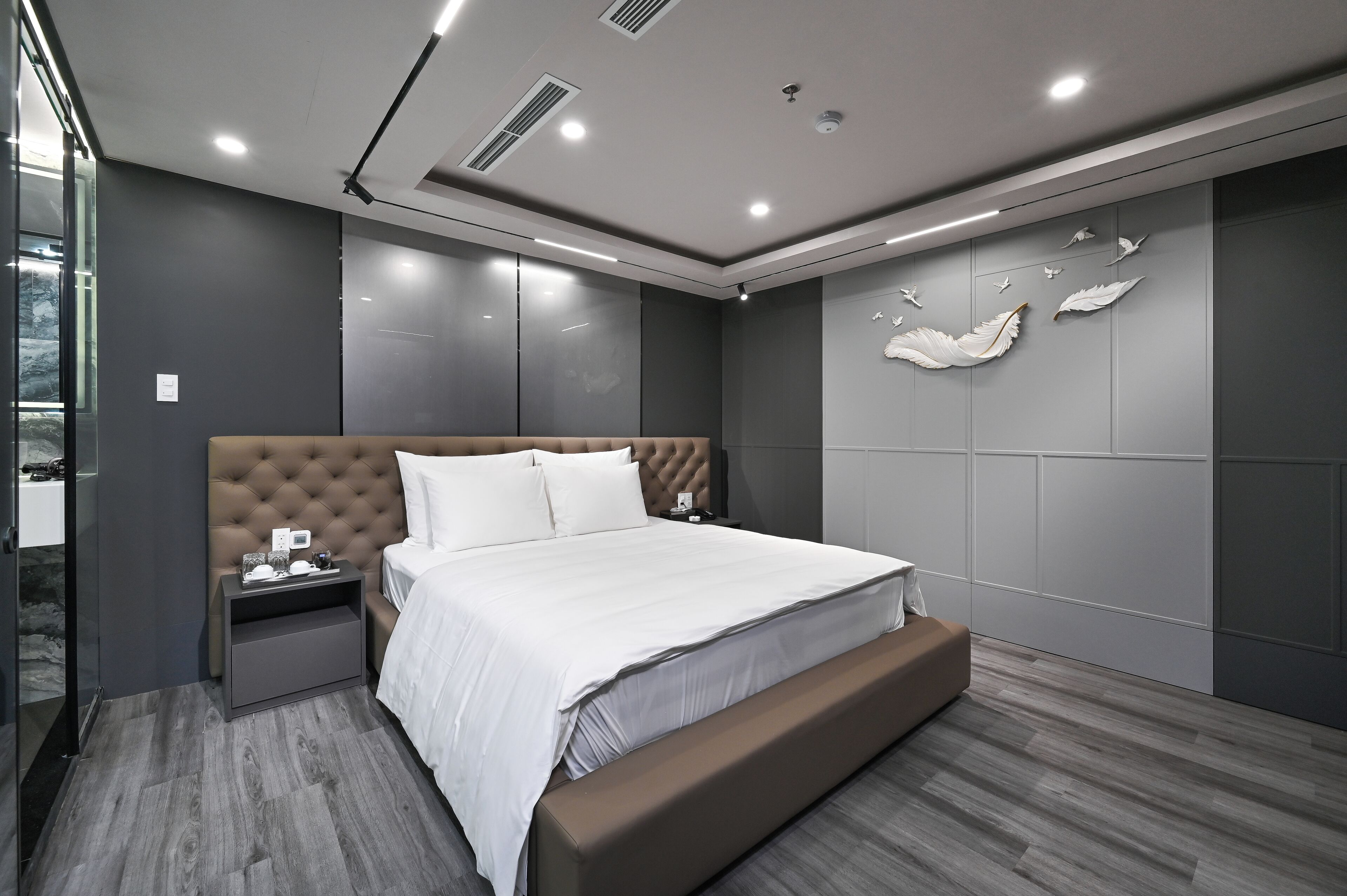 A modern bedroom with a large bed, a nightstand, and a bench.