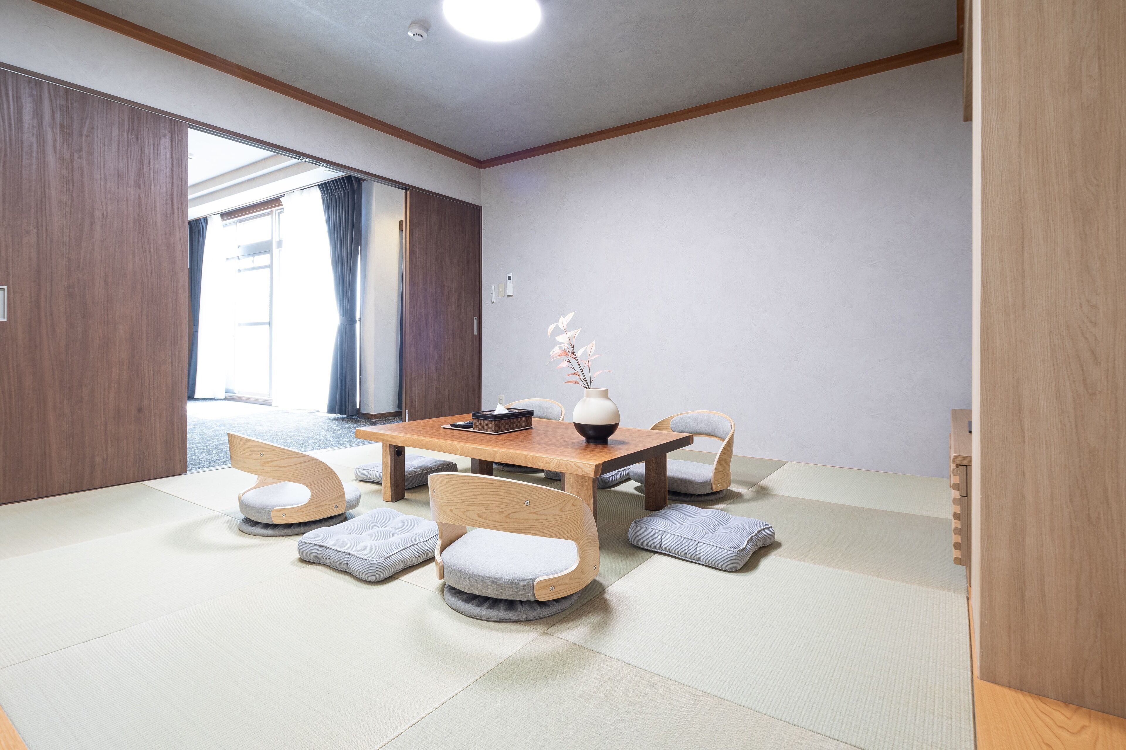 A room with tatami mat flooring, a wooden table, and four tatami mat chairs.