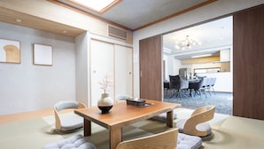 Une pièce de style japonais traditionnel, avec un sol recouvert de tatamis, une table à manger en bois et de petites chaises en bois.