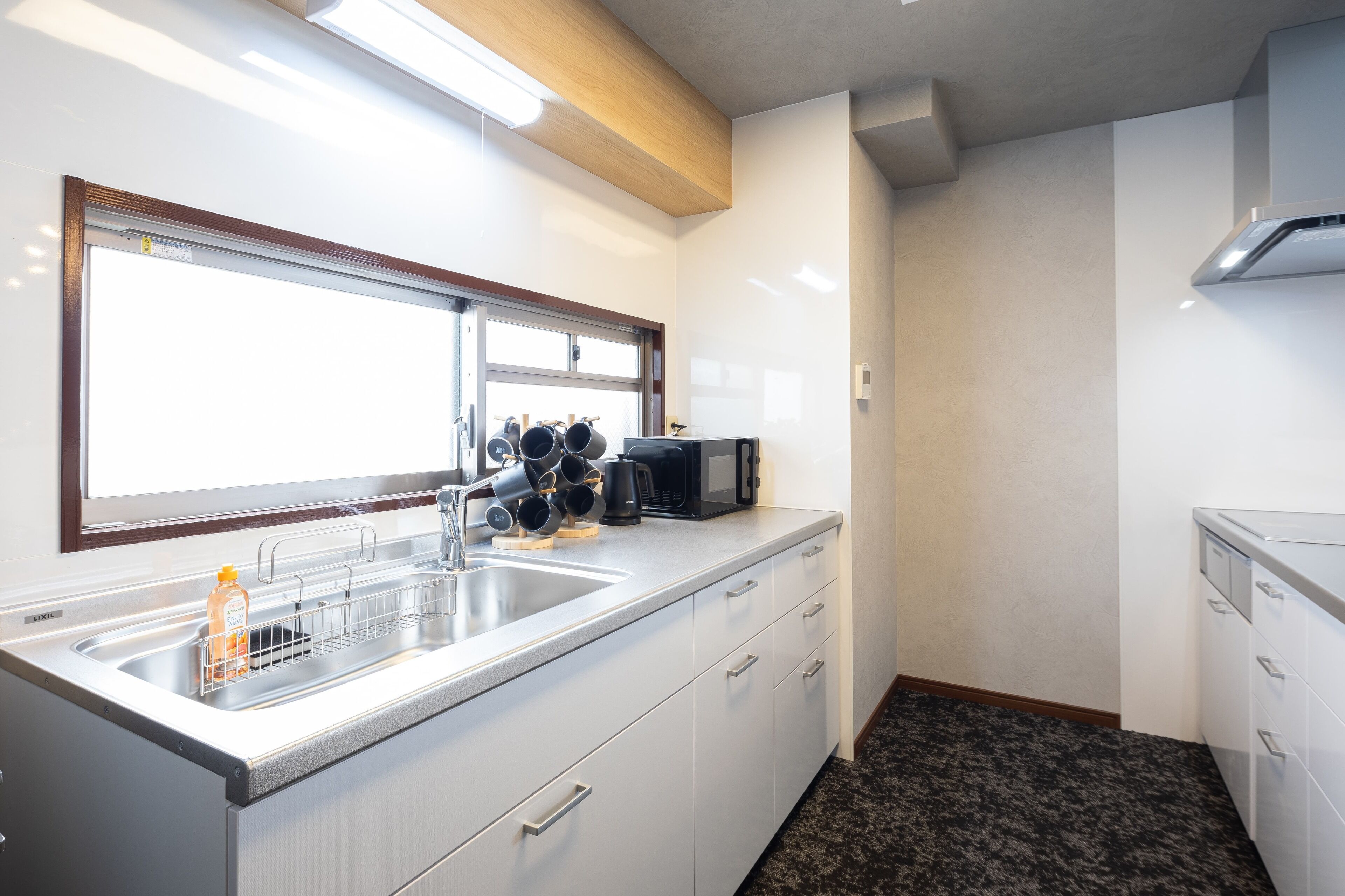A modern kitchen with a stainless steel sink, a microwave, and a window above the sink.