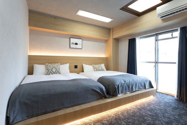 A double bed with a wooden headboard, a bedside table, and a large window with curtains. - b&Namba1 (Osaka)