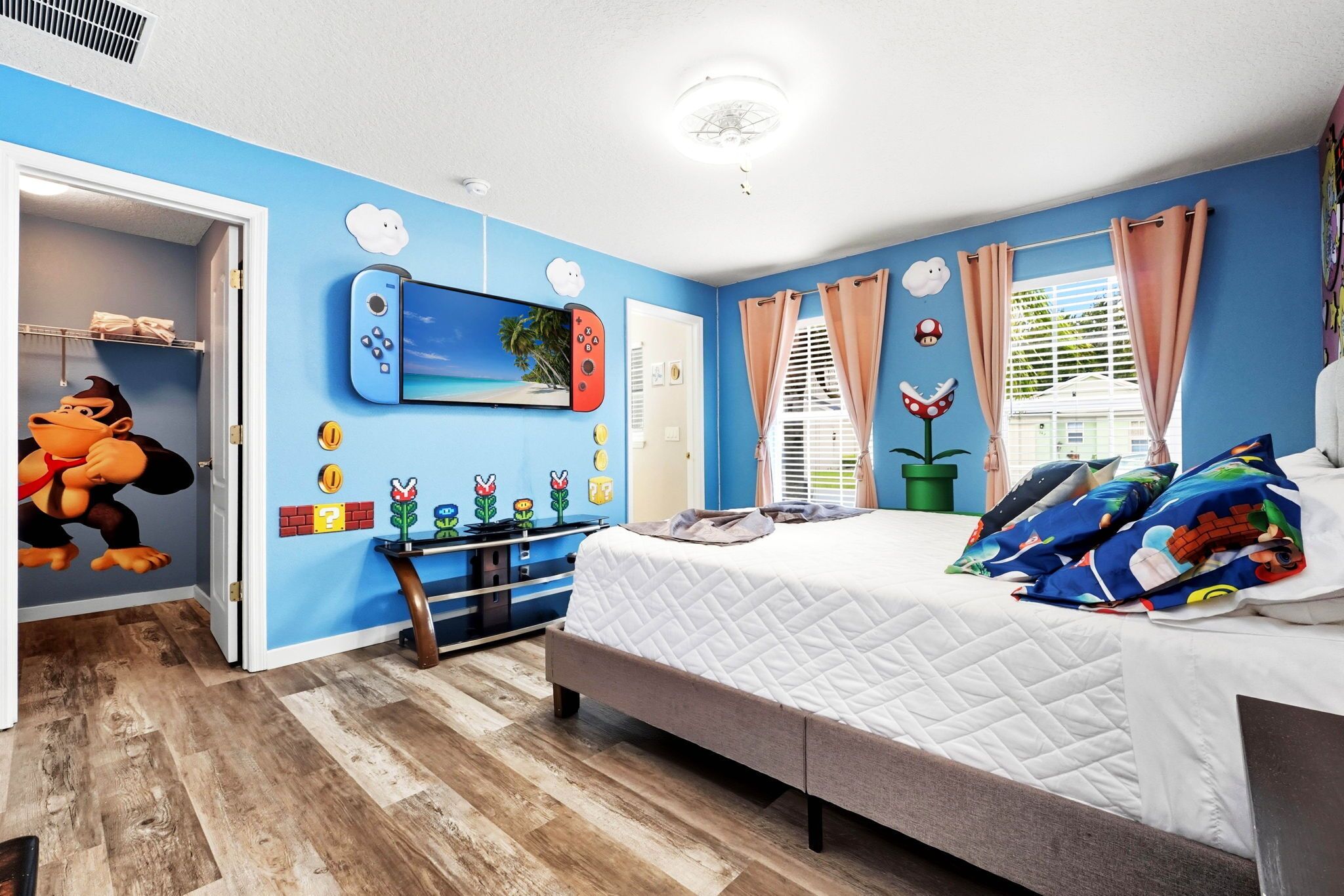 Un dormitorio con cama, armario, escritorio y silla, y una pared con un mural de Mario.