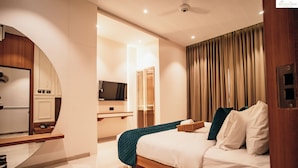 A modern hotel room with a bed, a TV, a mirror, and a wooden desk. - The Jeevan Inn (Shirdi)