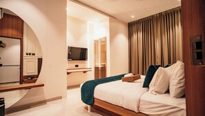 A modern hotel room with a bed, a TV, a mirror, and a wooden desk. - The Jeevan Inn (Shirdi)