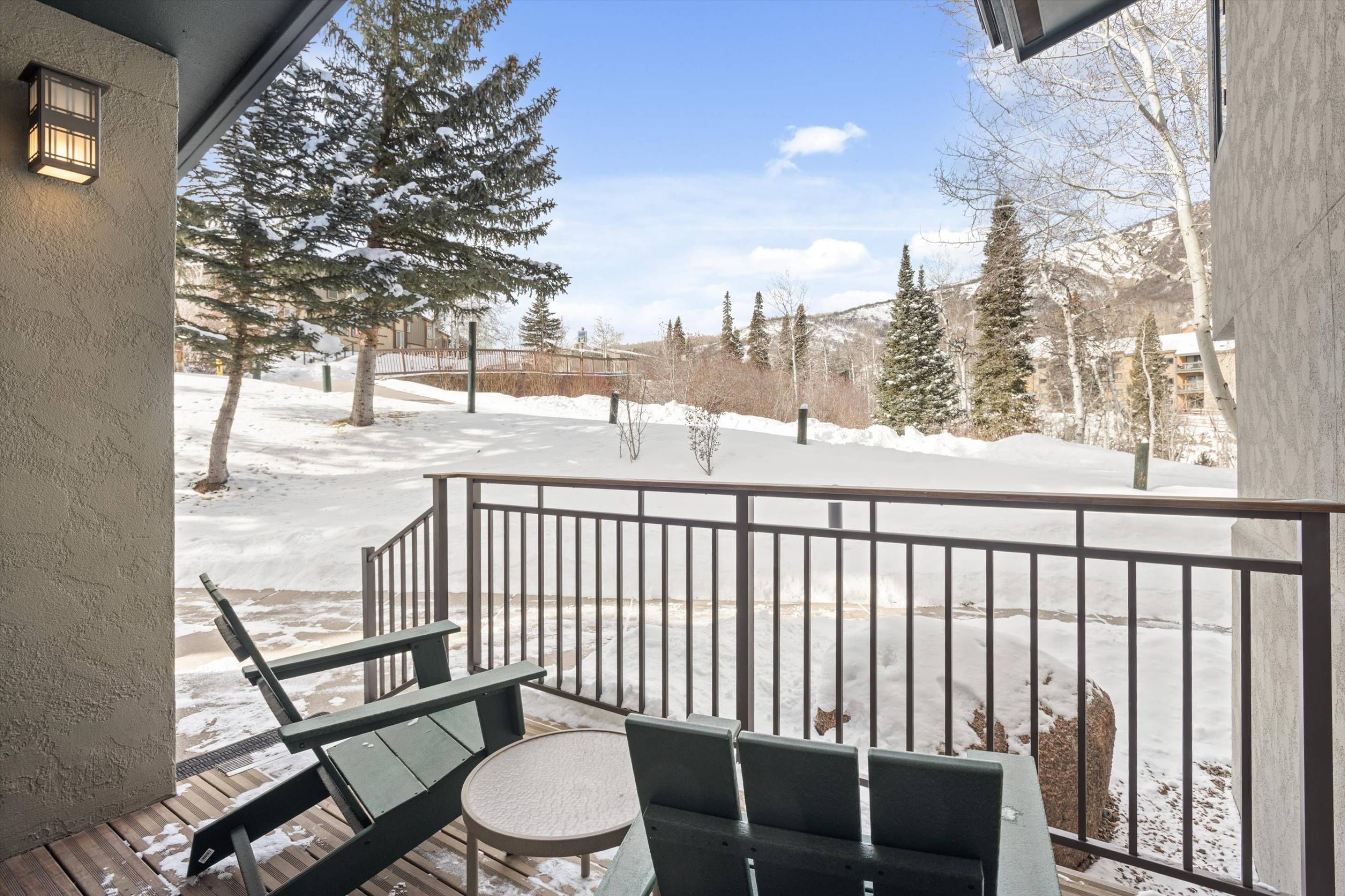 Un balcon donnant sur un paysage enneigé, avec des arbres et un bâtiment situé au loin.