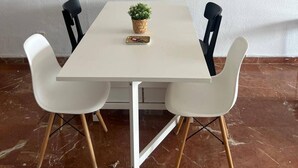 A dining area with a white table, four chairs, and a potted plant. - Plaza de la Magdalena II (Seville)