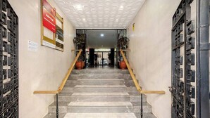 A staircase with marble steps and wooden handrails, leading to a door with a geometric pattern. - Plaza de la Magdalena II (Seville)