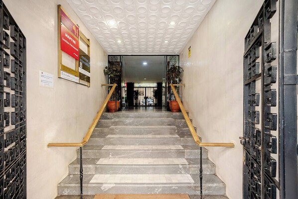 A staircase with marble steps and wooden handrails, leading to a door with a geometric pattern. - Plaza de la Magdalena II (Seville)