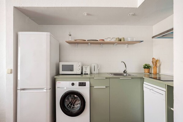 A compact kitchen with a refrigerator, microwave, toaster, sink, and washing machine. - Plaza de la Magdalena II (Seville)