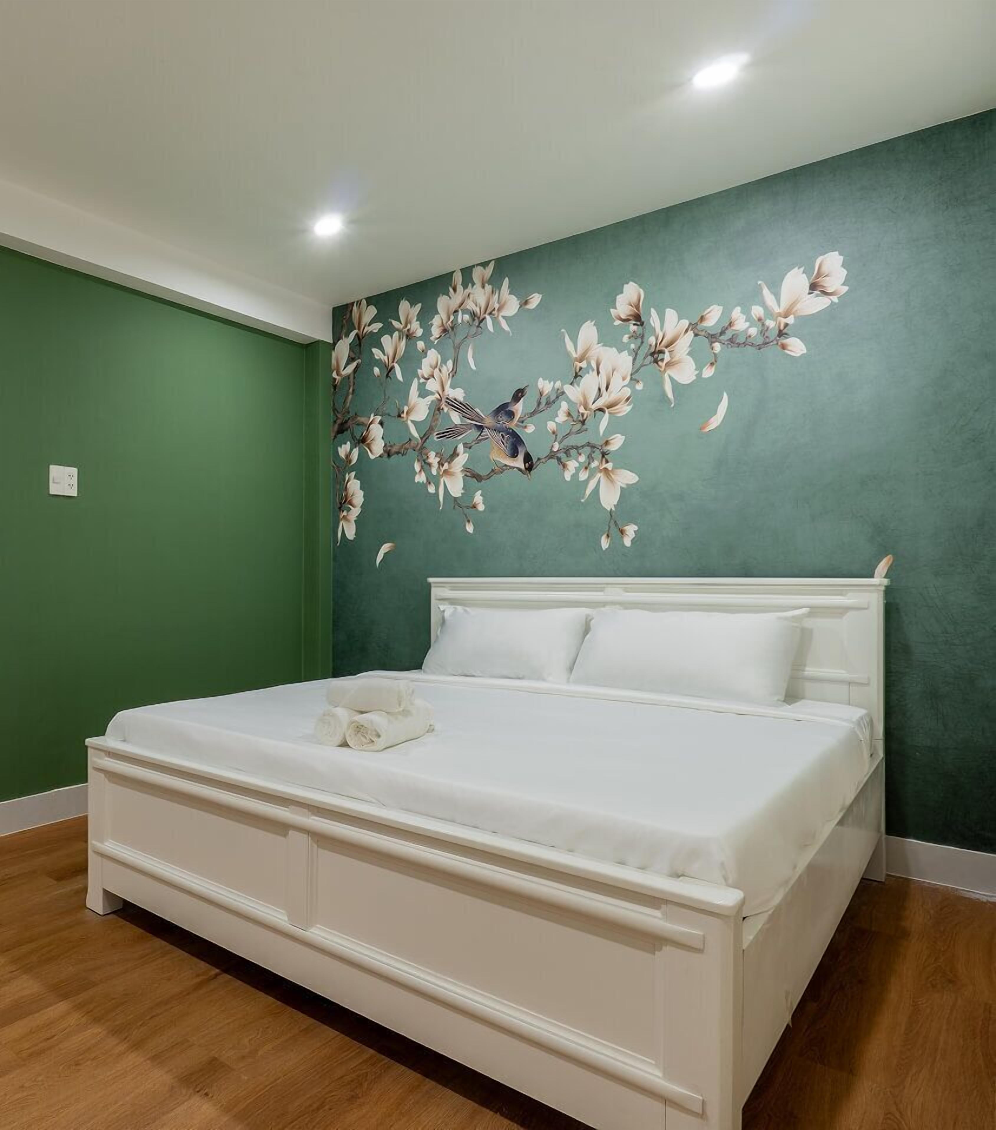 Un dormitorio con una cama grande, paredes verdes y un mural floral.