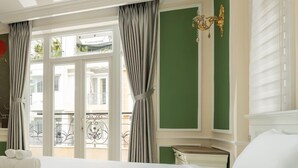 Camera d'albergo con un letto grande, un comodino, un lampadario e vista sul balcone esterno.