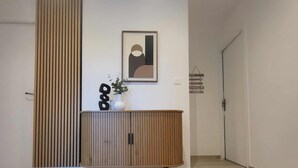 En modern inredning med ett träskåp, ett inramat abstrakt konstverk och en krukväxt.