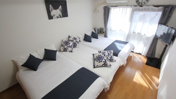 A hotel room with two beds, a clock, a TV, and a window with curtains. - Cozy Stay in Nakano Honcho - 7min to Shin-Nakano, 2 Stops to Shinjuku(33) (中野区本町)
