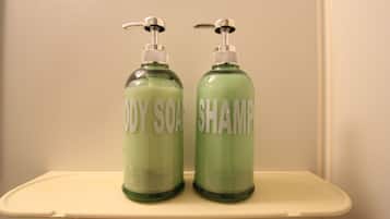 Zwei grüne Flaschen mit Duschseife und Shampoo auf einem weißen Regal.