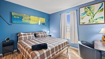 A bedroom with a bed, a nightstand, a lamp, a desk, and a chair.