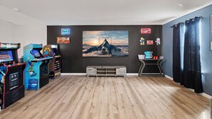 A room with wooden flooring, arcade games, a large movie poster, and a popcorn stand. - 5 BR King Size Beds Pickleball, Pool 25 mi to COTA (Bastrop)