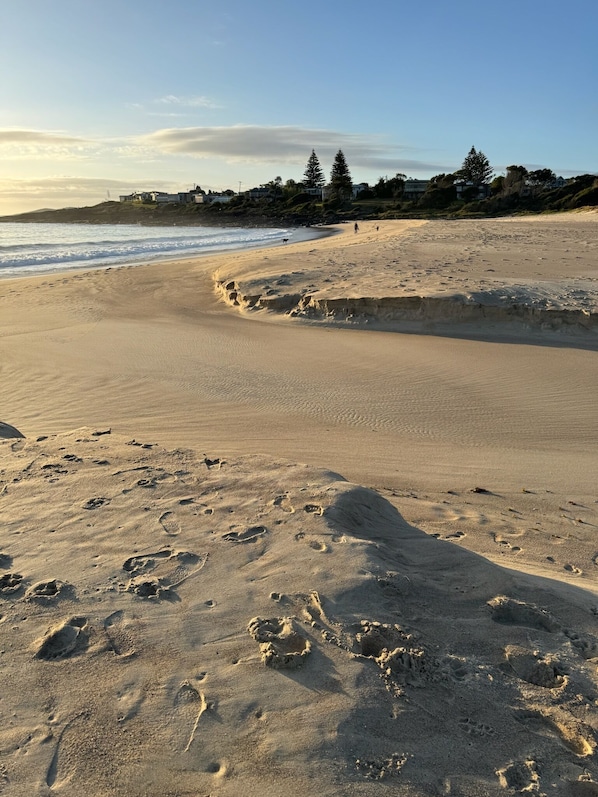 A beach with footprints and a curved shoreline.