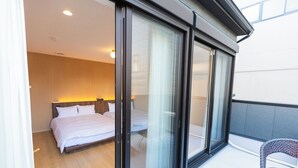 Une chambre d’hôtel avec un lit, un balcon avec une chaise et une grande porte-fenêtre coulissante.