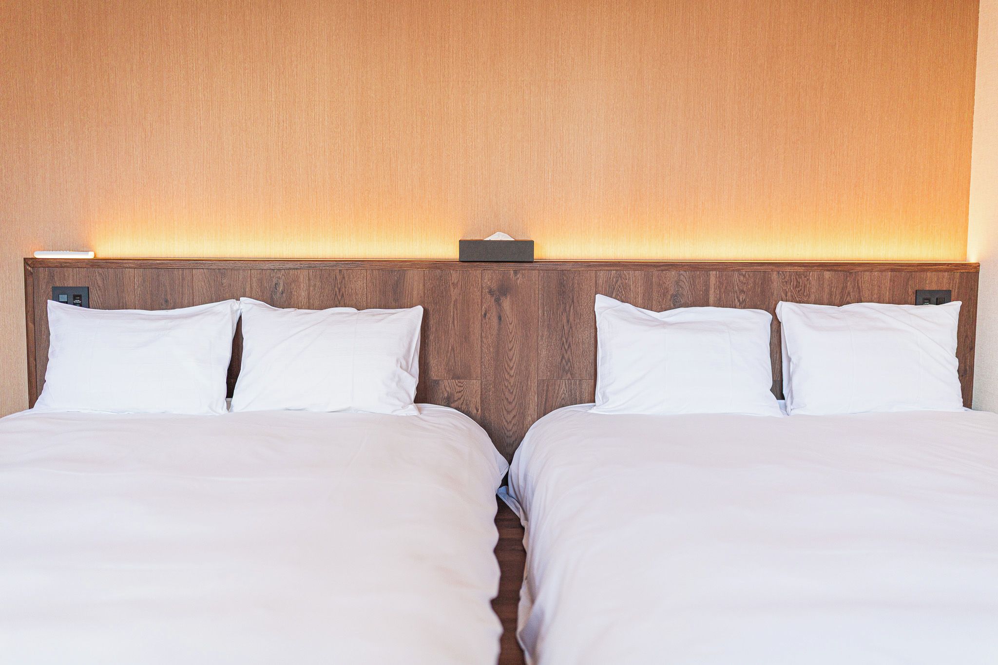 A double bed with a wooden headboard and a tissue box on it.