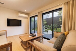 A modern living room with a sofa, a wooden table, and a TV mounted on the wall. - b&FLAT-Hanazono (Osaka)