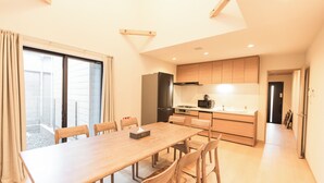 Une cuisine moderne avec des meubles de rangement en bois, une table à manger avec des chaises et une grande fenêtre avec des rideaux.