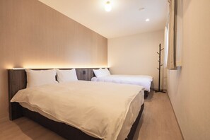 A hotel room with a large bed, a smaller bed, and a wardrobe. - b&FLAT-Hanazono (Osaka)