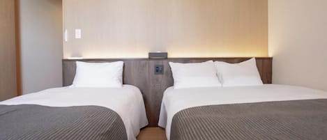 A hotel room with two beds, a wooden headboard, and a bedside table with a lamp.