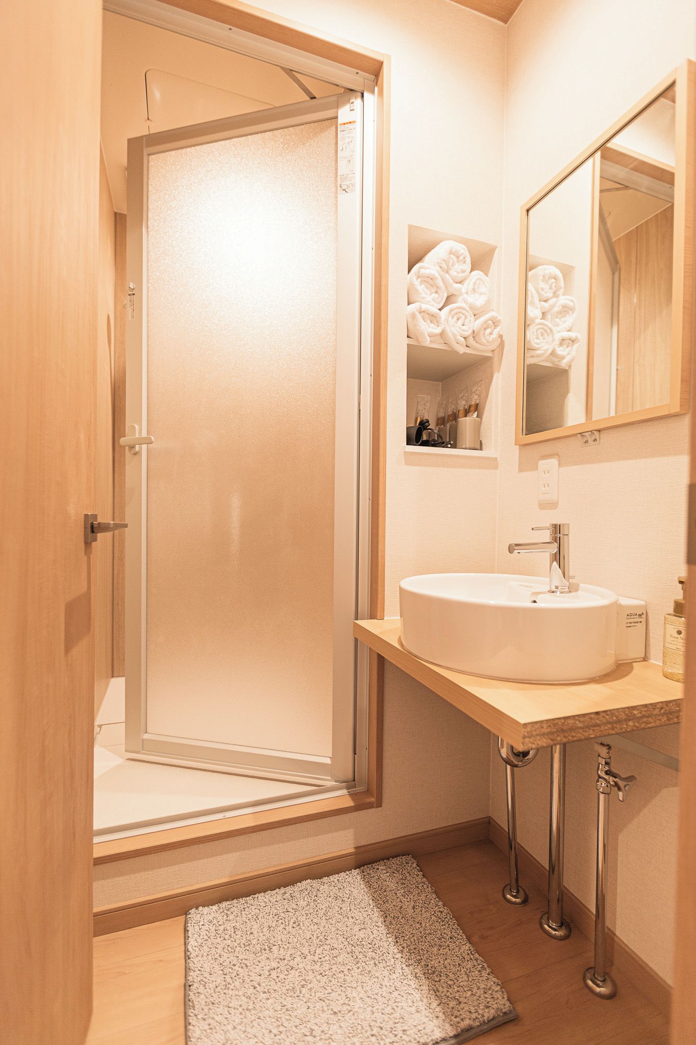 A bathroom with a glass shower enclosure, a sink with a mirror above, and a towel rack with towels.