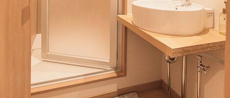 A bathroom with a glass shower enclosure, a sink with a mirror above, and a towel rack with towels.